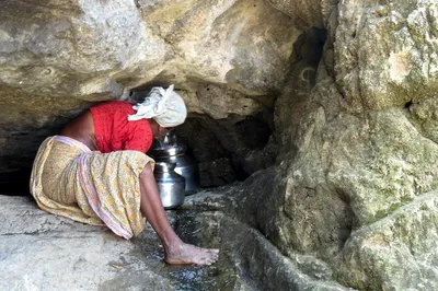 Woman storing food containers in a rockface.